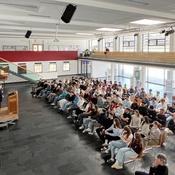 Roman Höllbacher (Künstlerischer Leiter Initiative Architektur) spricht vor Schüler*innen der HTL Saalfelden zur Abwicklung und Vergabe des Architekturpreis Land Salzburg.