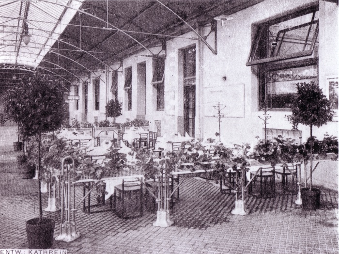 Die Gastgärten der Bahnhofsrestaurationen befanden sich unter den Seitenhallen der großen Stahlhalle, welche heute nicht mehr montiert sind. – Die Ausgestaltung der Restaurants erfolgte im Stil der Wiener Werkstätte - sogar der Josef Hoffmann Stuhl aus dem Cabaret Fledermaus ist zu sehen. Innenarchitektur: Heinrich Kathrein