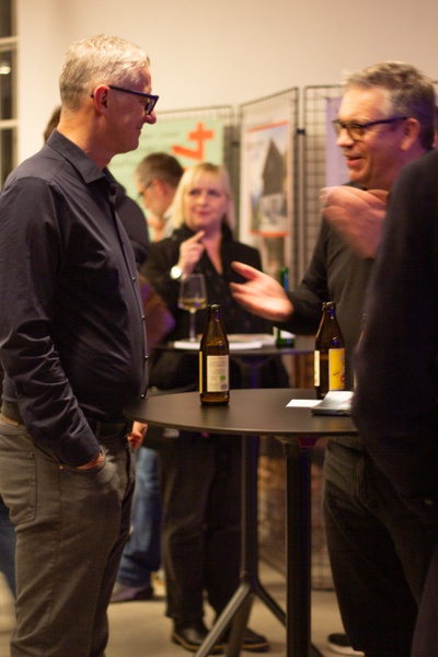 Die Gäste des Abends führen angeregte Gespräche über das Thema an der Bar.